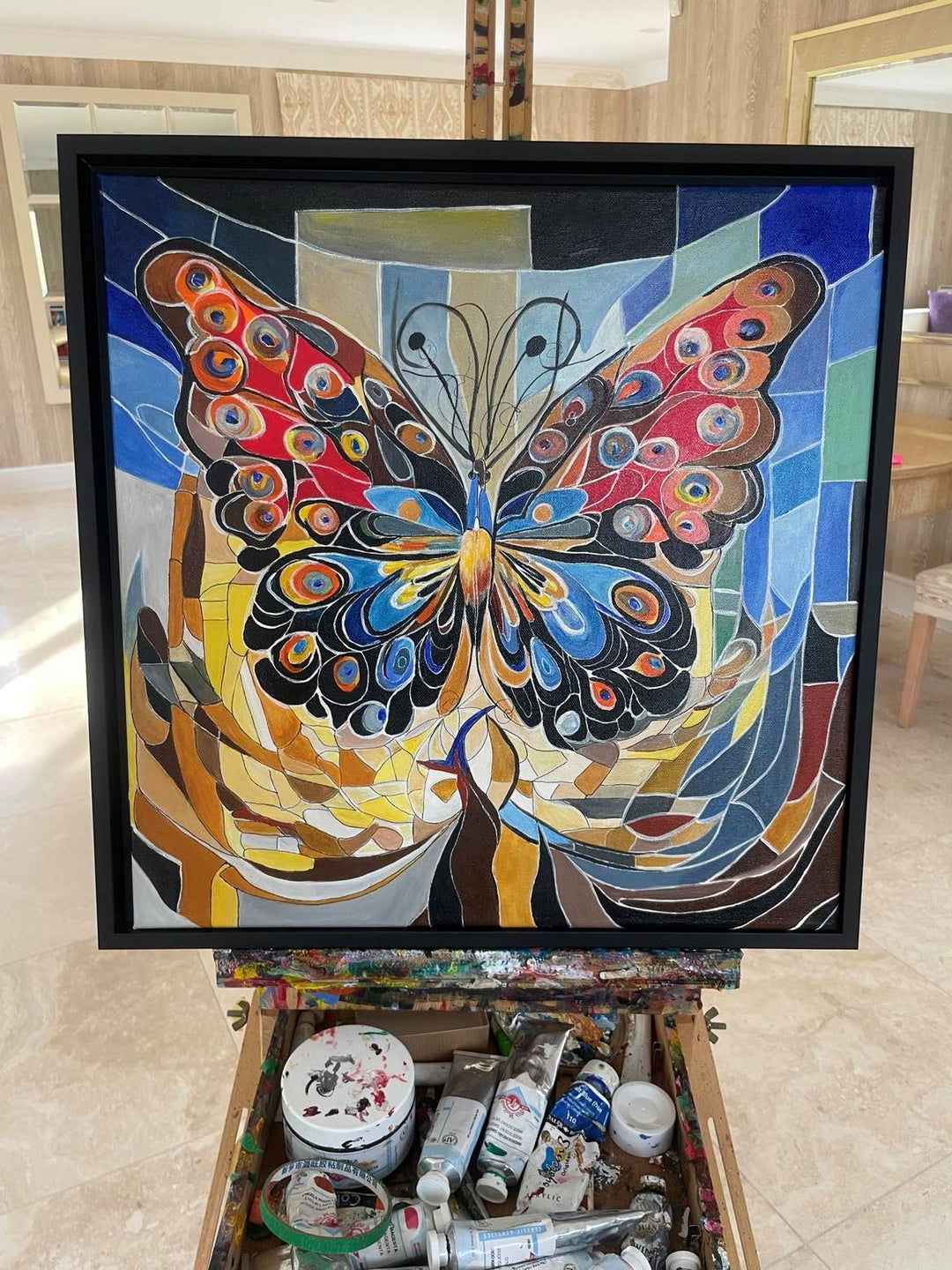 Abstract painting of a vibrant butterfly with patterned wings in red, blue, and orange tones, set against a mosaic-style background.

