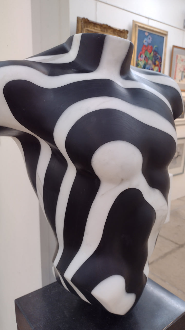 Striking male torso sculpture crafted from Italian white marble and slate, featuring bold organic contour lines in high-contrast black and white, displayed on a dedicated base for interior presentation.