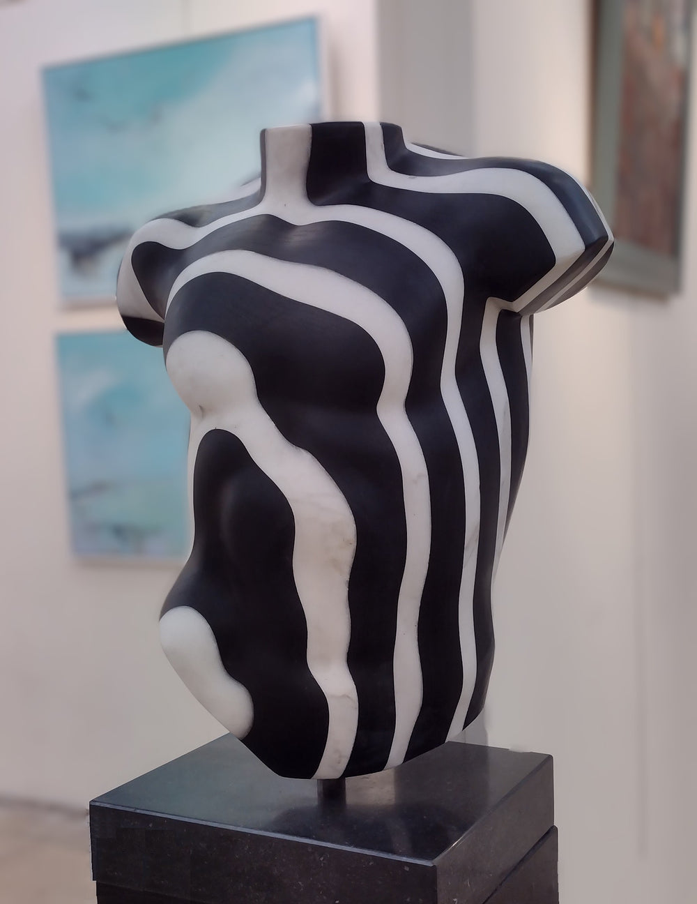 Striking male torso sculpture crafted from Italian white marble and slate, featuring bold organic contour lines in high-contrast black and white, displayed on a dedicated base for interior presentation.