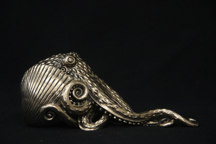 Polished bronze sculpture of an octopus with intricately detailed tentacles and textured body, shown against a black background.
