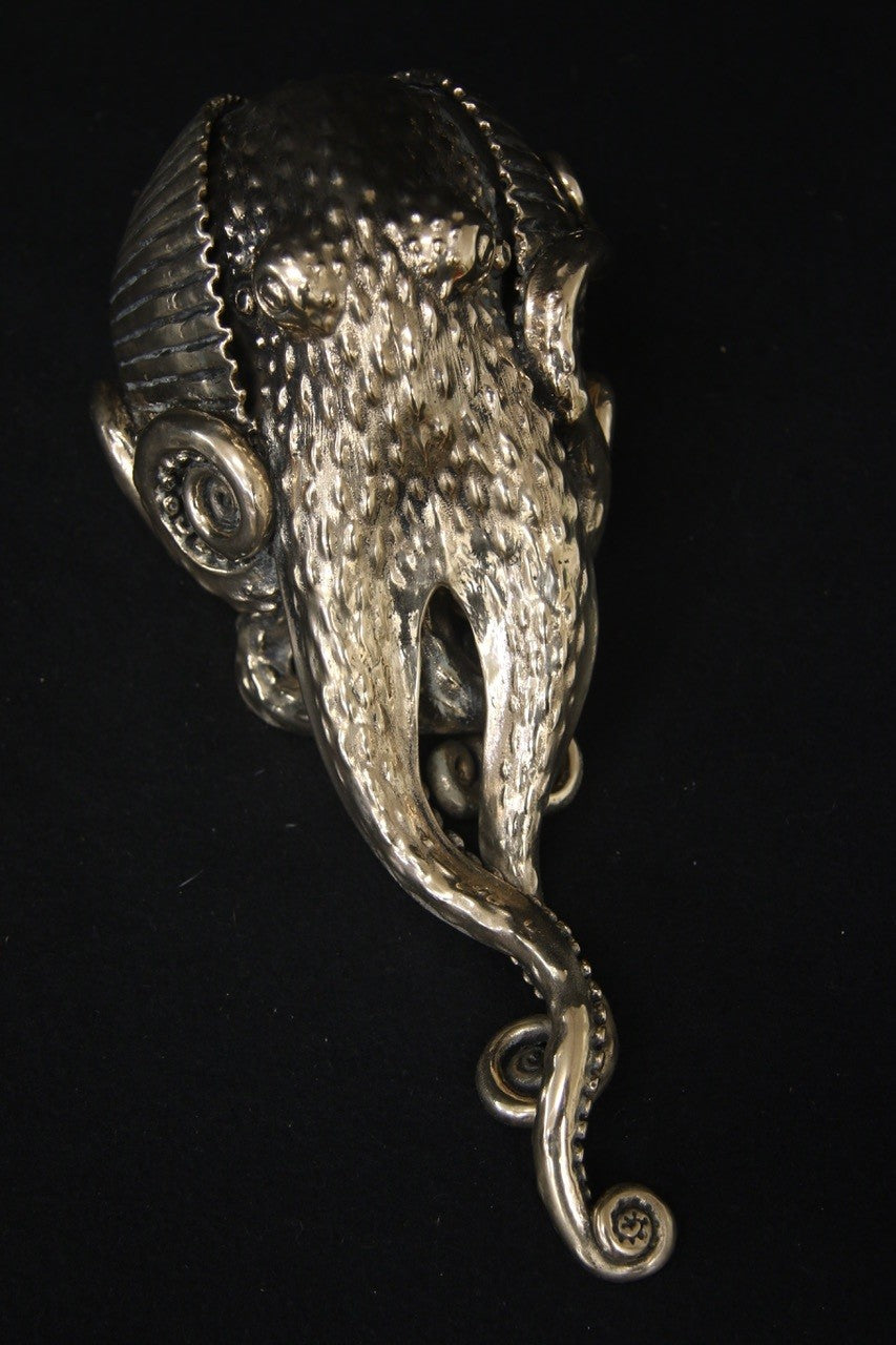 Polished bronze sculpture of an octopus with intricately detailed tentacles and textured body, shown against a black background.