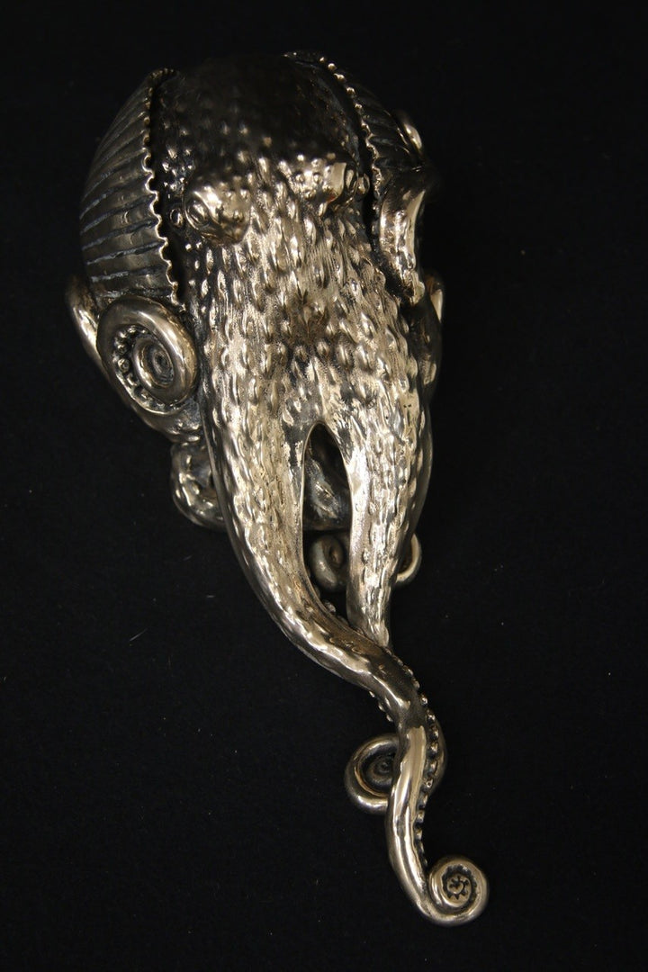 Polished bronze sculpture of an octopus with intricately detailed tentacles and textured body, shown against a black background.