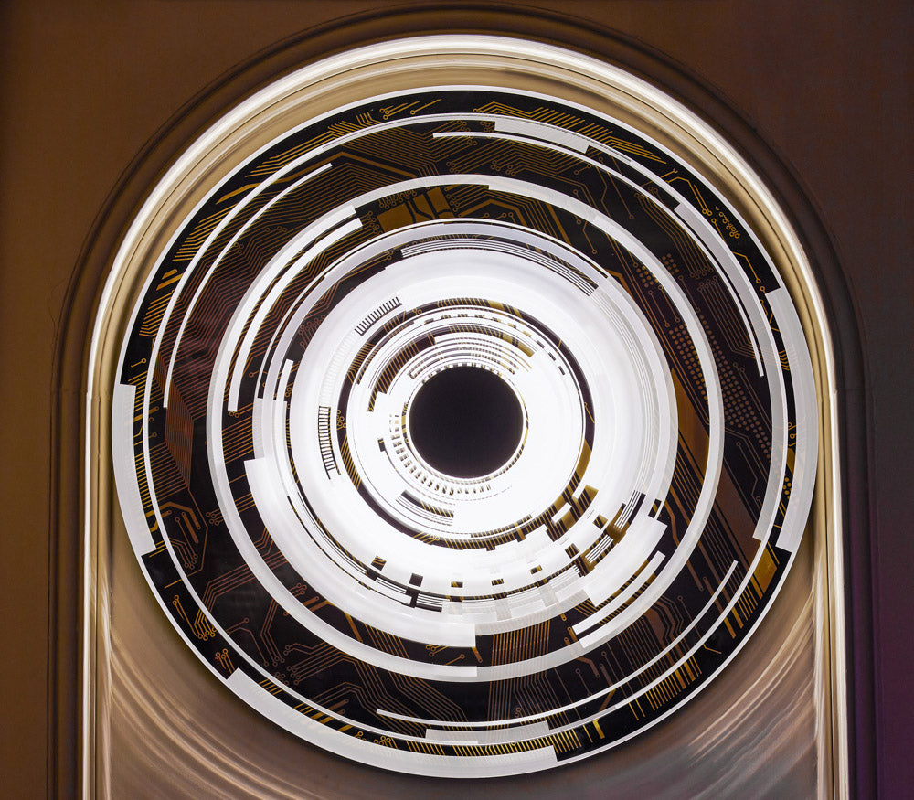 The Portal by Ben Rousseau – a circular illuminated artwork blending acrylic, LED, and brass. Featuring concentric rings and circuit-inspired patterns in gold, white, and black, it transforms technology into art and light into architectural sculpture.