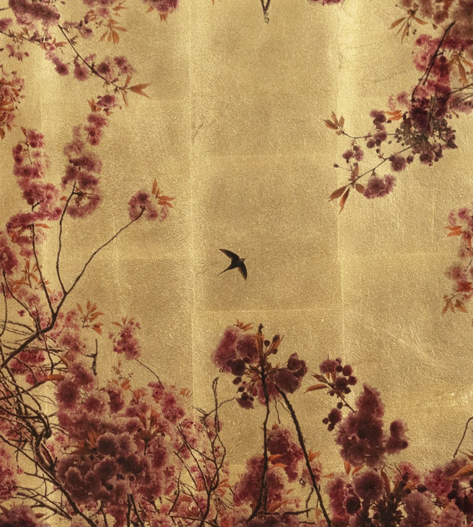 Robert Pereira Hind’s Prunus from the Out of Eden series — a delicate mixed media portrayal of cherry blossom branches in full bloom, encircling a single swallow in flight. Pink and magenta petals contrast against a luminous gold-leaf background, with subtle autumnal leaves adding warmth. Created using acrylic paint and organic photographic pigment on a gilded wooden panel, the surface is finished with shellac and art glazes to develop a rich, natural patina over time.