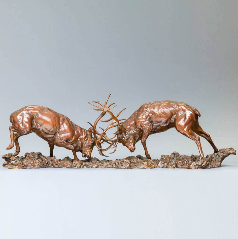 Bronze sculpture of two red deer stags in mid-rut, antlers locked in a dynamic head-to-head clash, highly detailed musculature and patina, mounted on a textured bronze base.