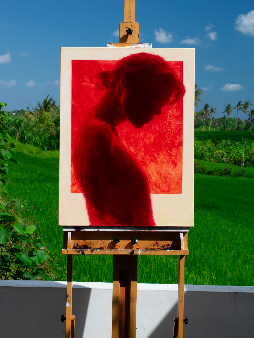 Oil on canvas painting by Dan Bullock, titled Radiance. A striking silhouette portrait of a woman in profile, painted entirely in deep crimson red within a bold rectangular frame, set against a neutral canvas ground. The figure’s bowed head and soft edges evoke intimacy and contemplation, with rich tonal depth and glowing intensity.