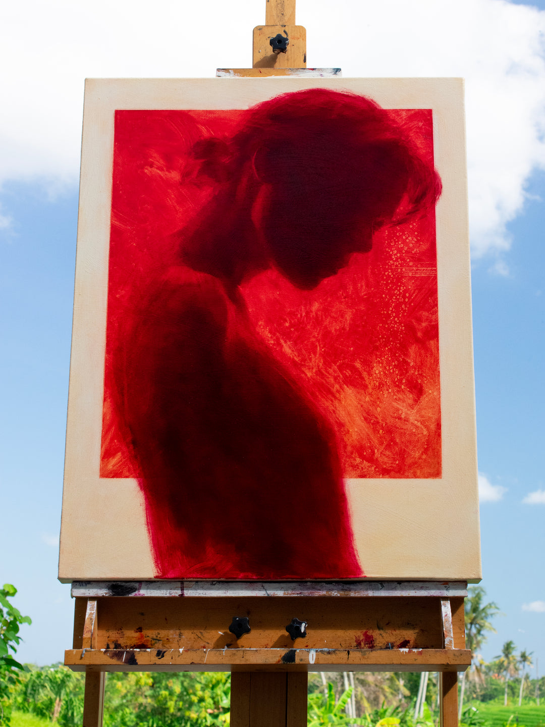 Oil on canvas painting by Dan Bullock, titled Radiance. A striking silhouette portrait of a woman in profile, painted entirely in deep crimson red within a bold rectangular frame, set against a neutral canvas ground. The figure’s bowed head and soft edges evoke intimacy and contemplation, with rich tonal depth and glowing intensity.