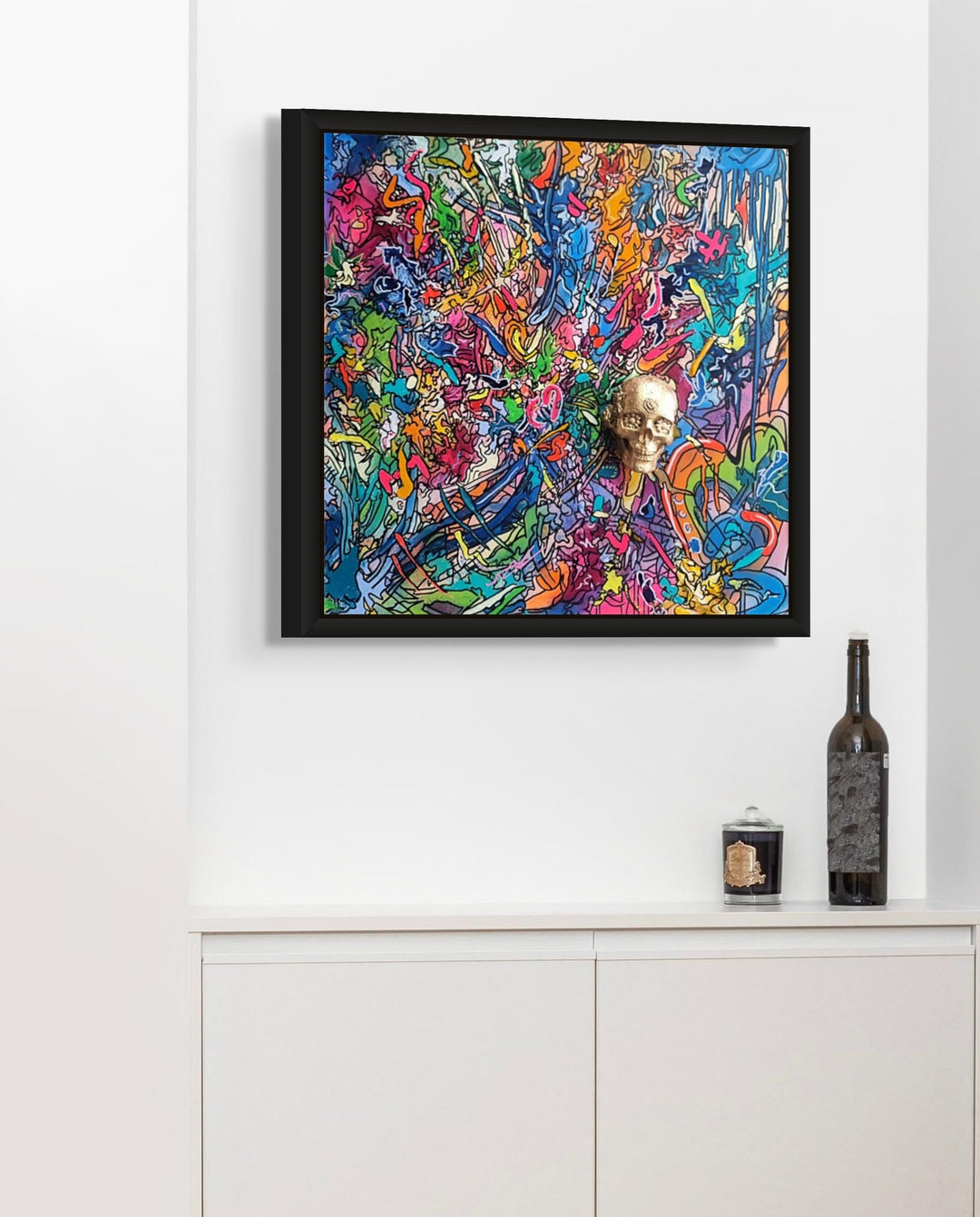 A vibrant abstract artwork filled with layered graffiti-style lines, bold colours and energetic mark-making, centred around a gold 3D skull emerging from the canvas.