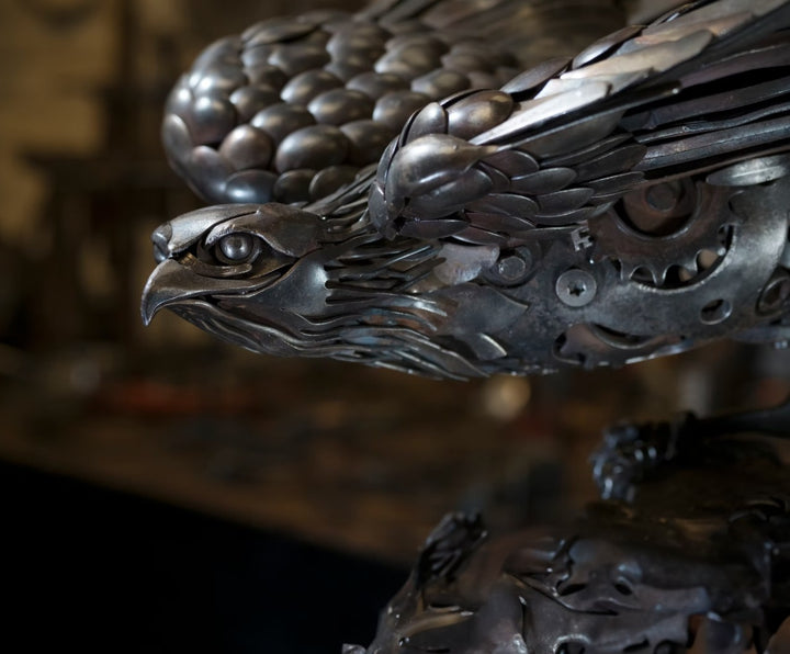Close-up of a handcrafted metal hawk sculpture with outstretched wings, captured with sparks in the background.