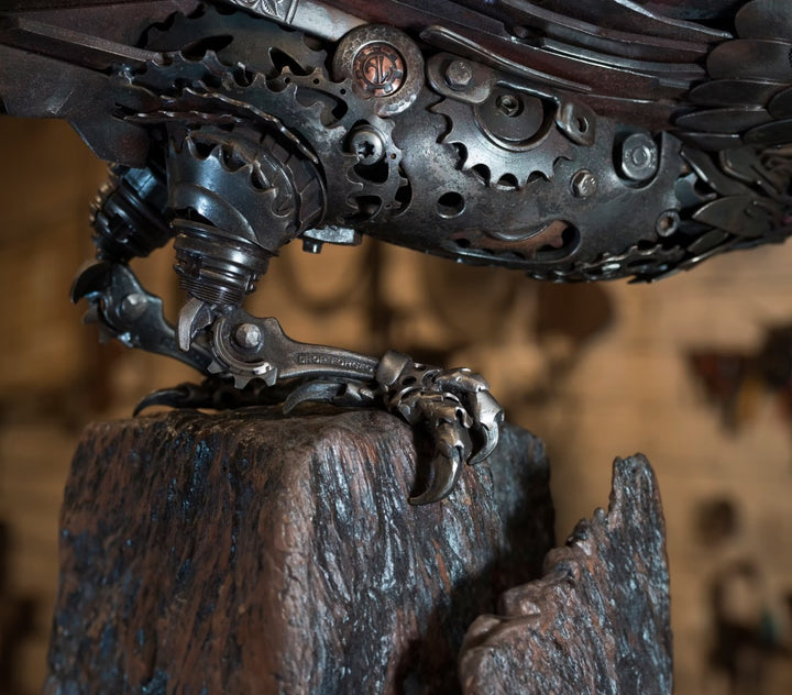 Close-up of a handcrafted metal hawk sculpture with outstretched wings, captured with sparks in the background.