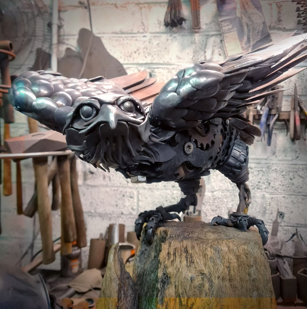 Close-up of a handcrafted metal hawk sculpture with outstretched wings, captured with sparks in the background.