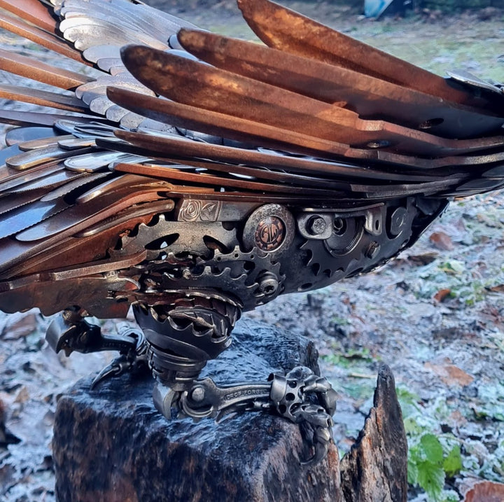 Close-up of a handcrafted metal hawk sculpture with outstretched wings, captured with sparks in the background.