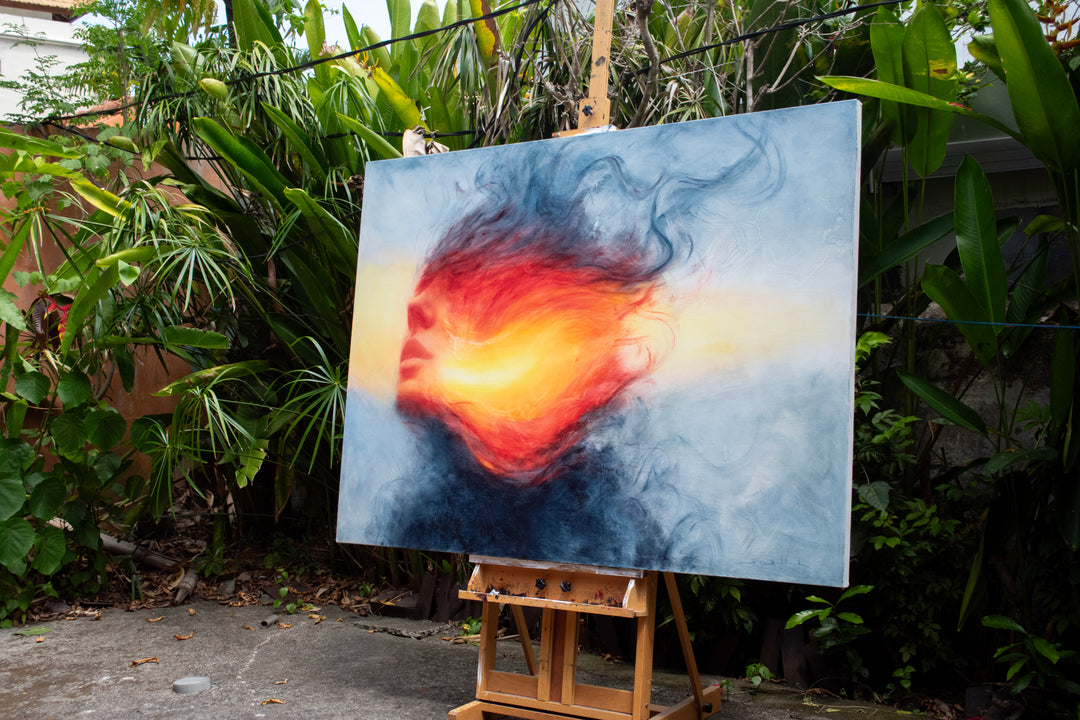 Large oil on canvas painting by Dan Bullock, titled Reverie. A dreamlike portrait of a female face in profile, dissolving into swirling colours of fiery red, orange, and golden yellow, contrasted with cool blue and smoky black tones. The composition radiates energy and motion, blending realism with abstraction.