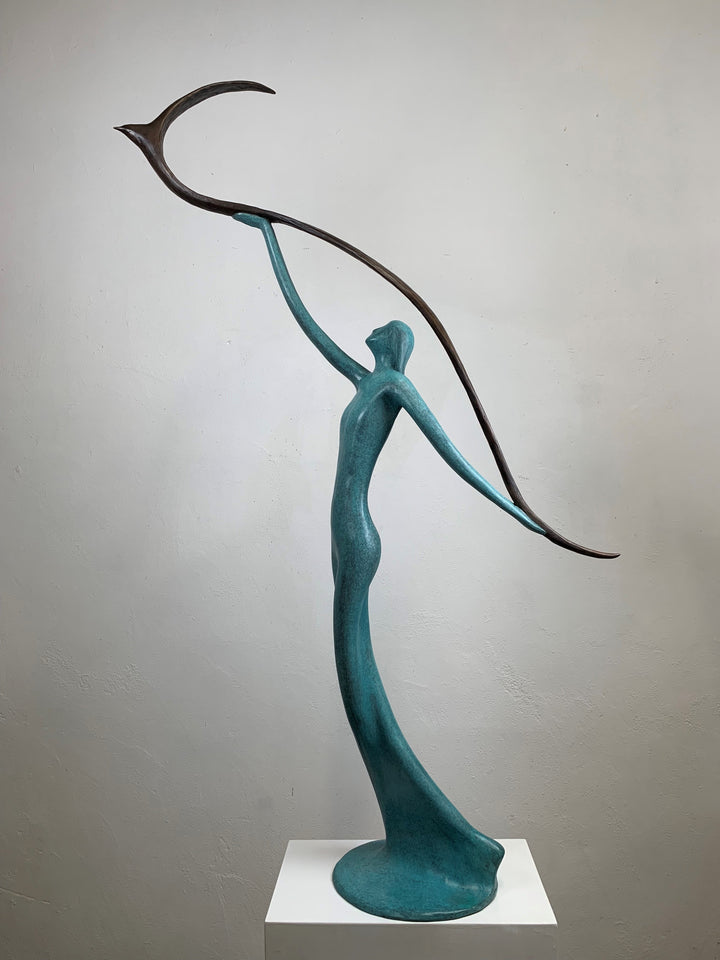 Graceful resin sculpture of an elongated teal figure reaching upward, releasing a stylised bird in flight.