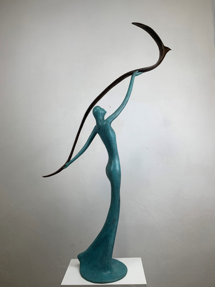 Graceful resin sculpture of an elongated teal figure reaching upward, releasing a stylised bird in flight.