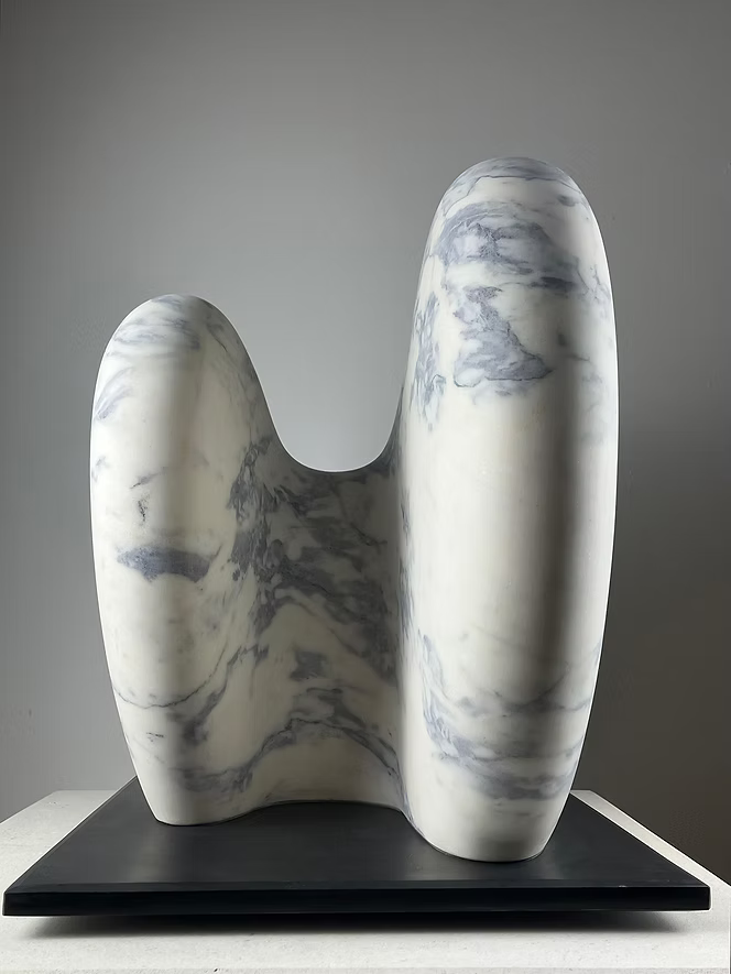 Jason Mulligan sculpture titled RISE, a one-off contemporary abstract artwork hand-carved from Portuguese marble. The sculpture features two large, rounded organic forms rising side by side, their surfaces polished smooth to reveal natural white marble with grey-blue veining. Presented on a black plinth, the piece embodies balance, unity, and quiet strength, blending modern minimalism with timeless stone carving traditions.