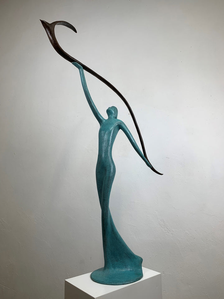 Graceful resin sculpture of an elongated teal figure reaching upward, releasing a stylised bird in flight.