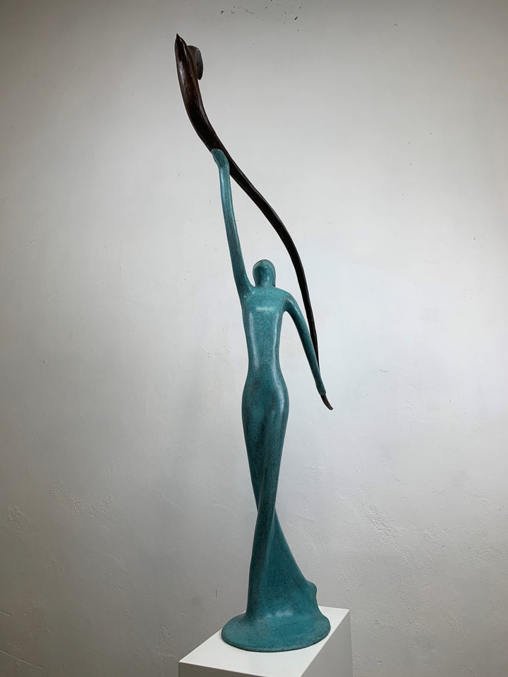 Graceful resin sculpture of an elongated teal figure reaching upward, releasing a stylised bird in flight.
