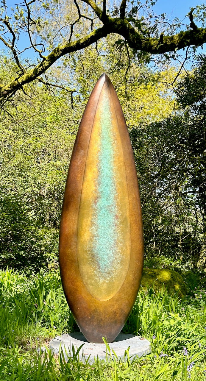 Monumental bronze sculpture by Dominic Welch, Rising Form VI, standing over 2.5 metres tall. The elongated leaf-like form features a smooth, tapering silhouette with a central turquoise-green patinated core against rich bronze tones. A powerful outdoor or architectural piece, it radiates elegance, presence, and organic energy.