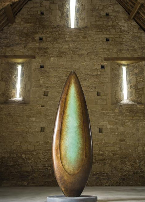 Monumental bronze sculpture by Dominic Welch, Rising Form VI, standing over 2.5 metres tall. The elongated leaf-like form features a smooth, tapering silhouette with a central turquoise-green patinated core against rich bronze tones. A powerful outdoor or architectural piece, it radiates elegance, presence, and organic energy.