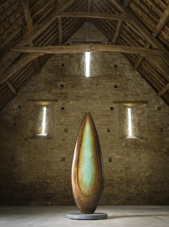 Monumental bronze sculpture by Dominic Welch, Rising Form VI, standing over 2.5 metres tall. The elongated leaf-like form features a smooth, tapering silhouette with a central turquoise-green patinated core against rich bronze tones. A powerful outdoor or architectural piece, it radiates elegance, presence, and organic energy.