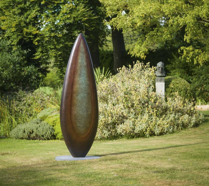 Monumental bronze sculpture by Dominic Welch, Rising Form VI, standing over 2.5 metres tall. The elongated leaf-like form features a smooth, tapering silhouette with a central turquoise-green patinated core against rich bronze tones. A powerful outdoor or architectural piece, it radiates elegance, presence, and organic energy.
