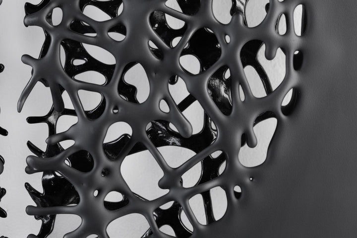 Tracy Nicholls glass wall sculpture Riven — a one-off artwork of two black glass panels forming an orb when placed side by side. The intricate webbed structure undulates with organic movement, featuring a satin-smooth exterior contrasting with a glossy black inner surface that glimmers through the open lace-like forms.