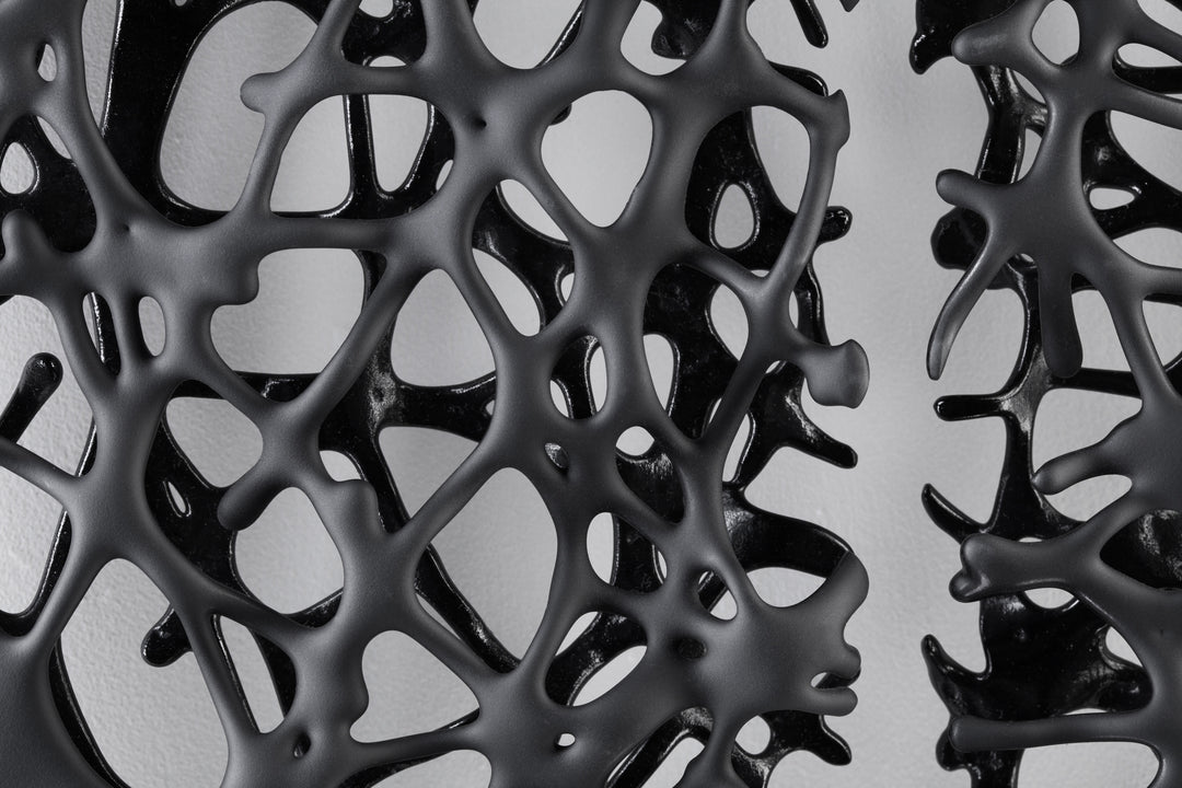 Tracy Nicholls glass wall sculpture Riven — a one-off artwork of two black glass panels forming an orb when placed side by side. The intricate webbed structure undulates with organic movement, featuring a satin-smooth exterior contrasting with a glossy black inner surface that glimmers through the open lace-like forms.