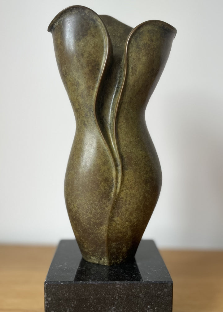 Elegant small bronze sculpture with a fluid, petal-like form and gently folding curves, finished in an earthy green-brown patina with subtle mottling, mounted on a polished black stone base.
