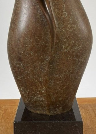 Tall, elegant bronze sculpture with flowing, petal-like curves and a rich earthy brown patina, its organic form rising gracefully from a polished black stone plinth.