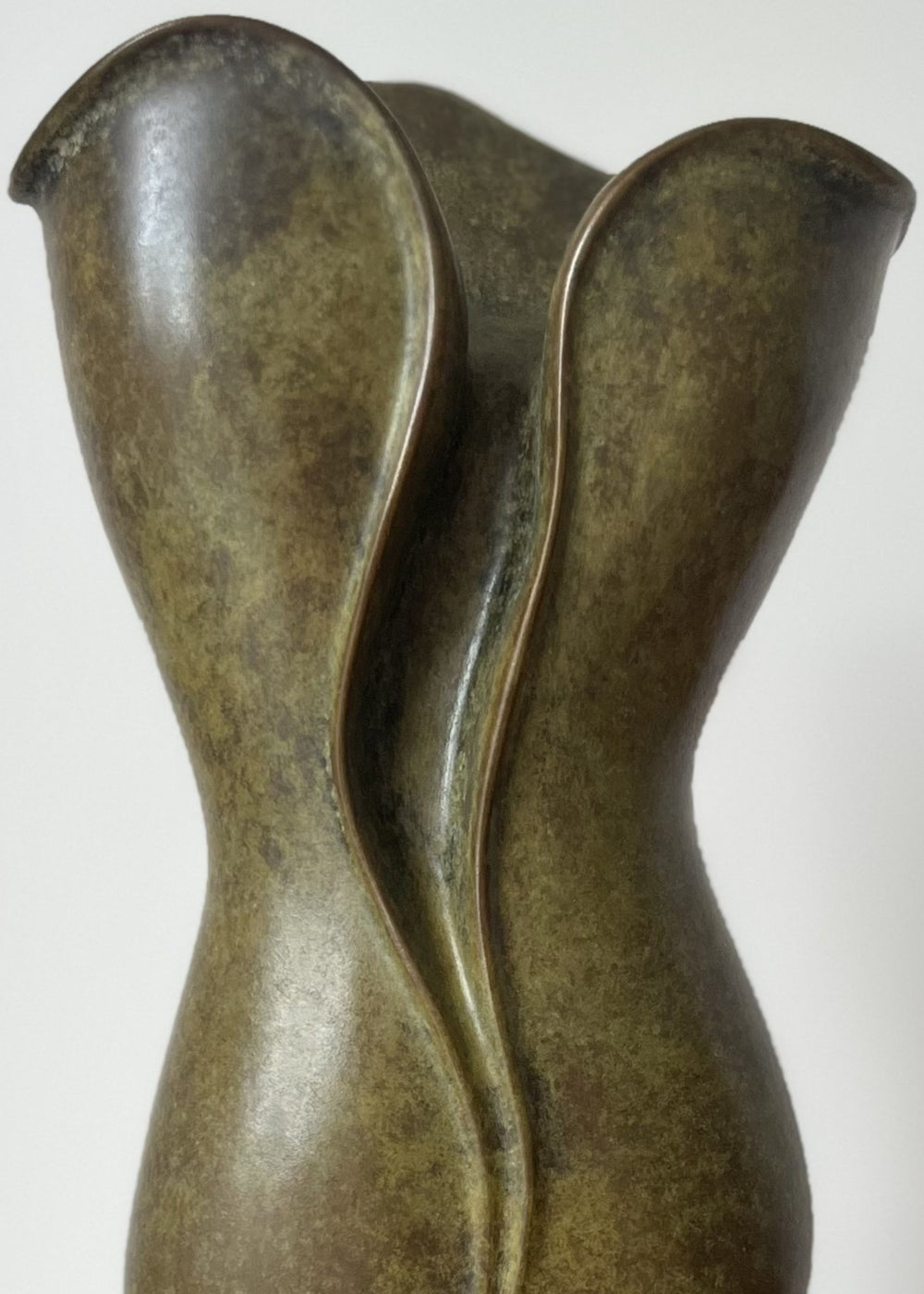 Elegant small bronze sculpture with a fluid, petal-like form and gently folding curves, finished in an earthy green-brown patina with subtle mottling, mounted on a polished black stone base.
