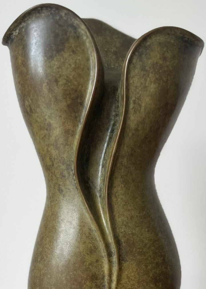 Elegant small bronze sculpture with a fluid, petal-like form and gently folding curves, finished in an earthy green-brown patina with subtle mottling, mounted on a polished black stone base.