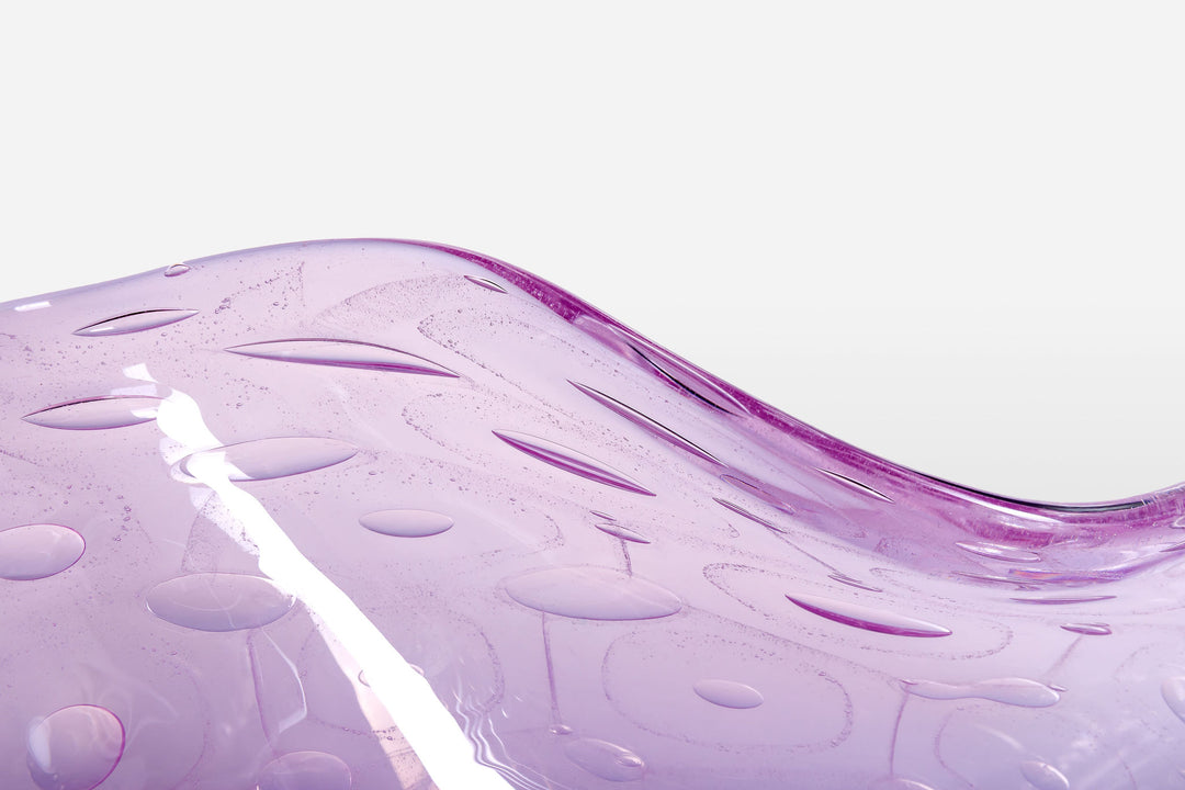 Delicately shaped lilac glass vessel with an organic rim and embossed bubble-like texture, set against a white background with soft reflection.