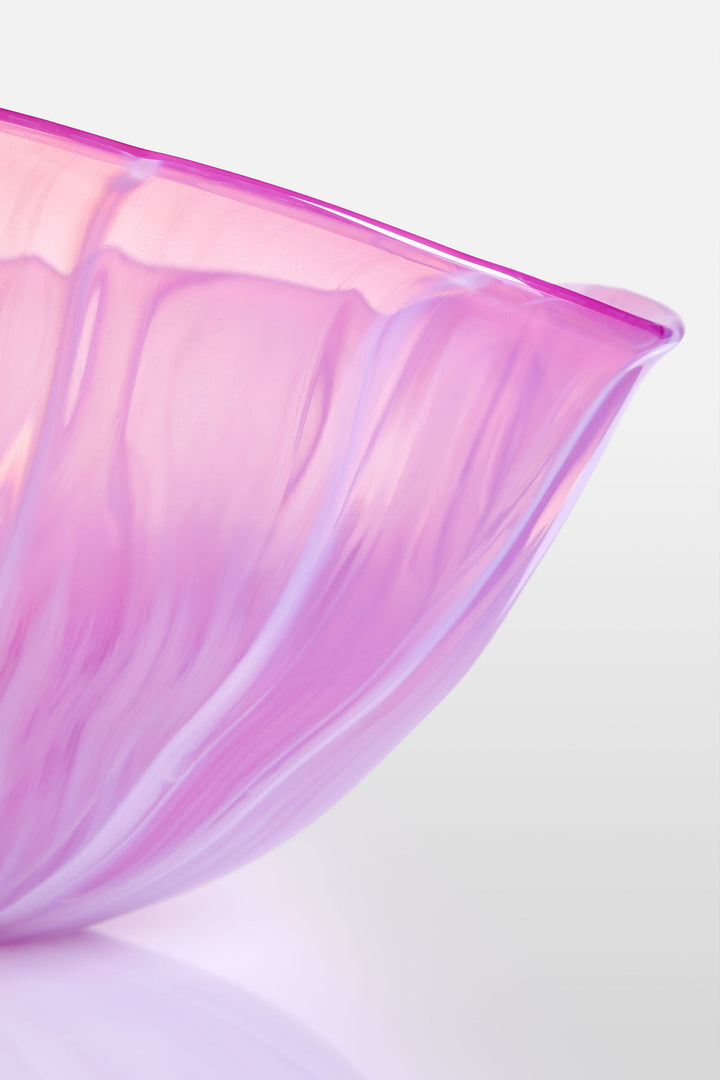 Delicately sculpted blown glass bowl in soft lilac and pink tones, with fluid contours and a translucent finish, displayed against a clean white background.