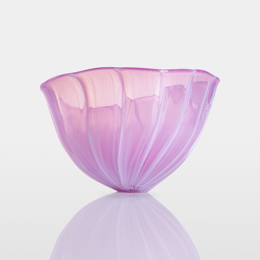 Delicately sculpted blown glass bowl in soft lilac and pink tones, with fluid contours and a translucent finish, displayed against a clean white background.