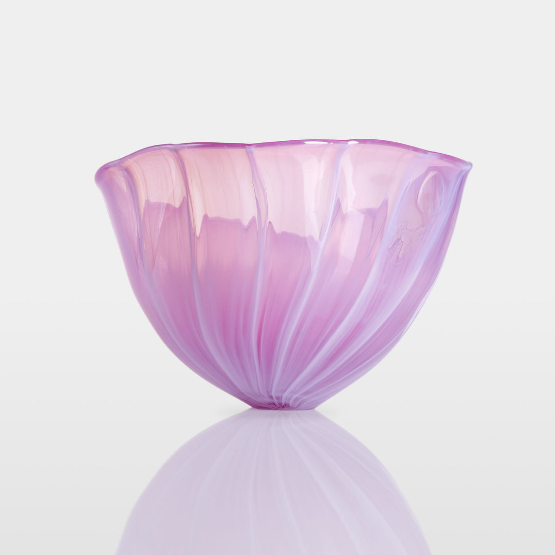 Delicately sculpted blown glass bowl in soft lilac and pink tones, with fluid contours and a translucent finish, displayed against a clean white background.