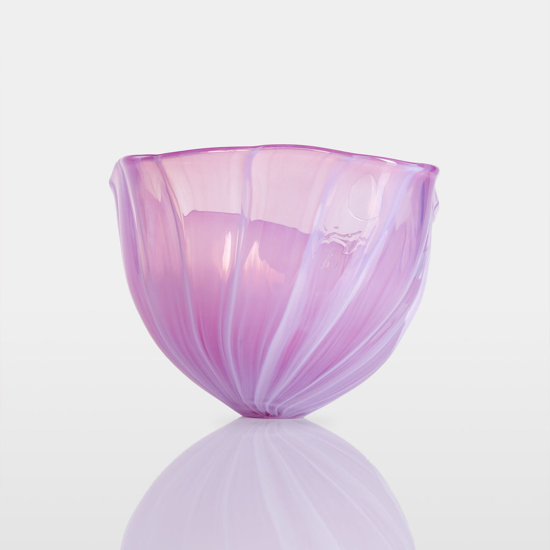 Delicately sculpted blown glass bowl in soft lilac and pink tones, with fluid contours and a translucent finish, displayed against a clean white background.