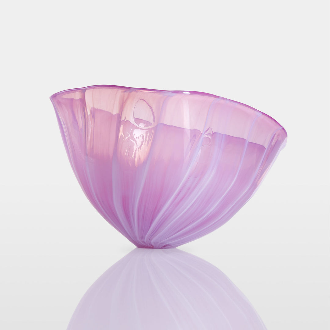Delicately sculpted blown glass bowl in soft lilac and pink tones, with fluid contours and a translucent finish, displayed against a clean white background.