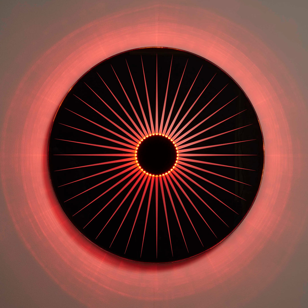 “Iris” by Ben Rousseau – a circular illuminated artwork crafted from engraved acrylic, combining nature’s geometry with digital precision. Red and amber light radiates from the centre, evoking the structure of a human iris in sculptural form.

