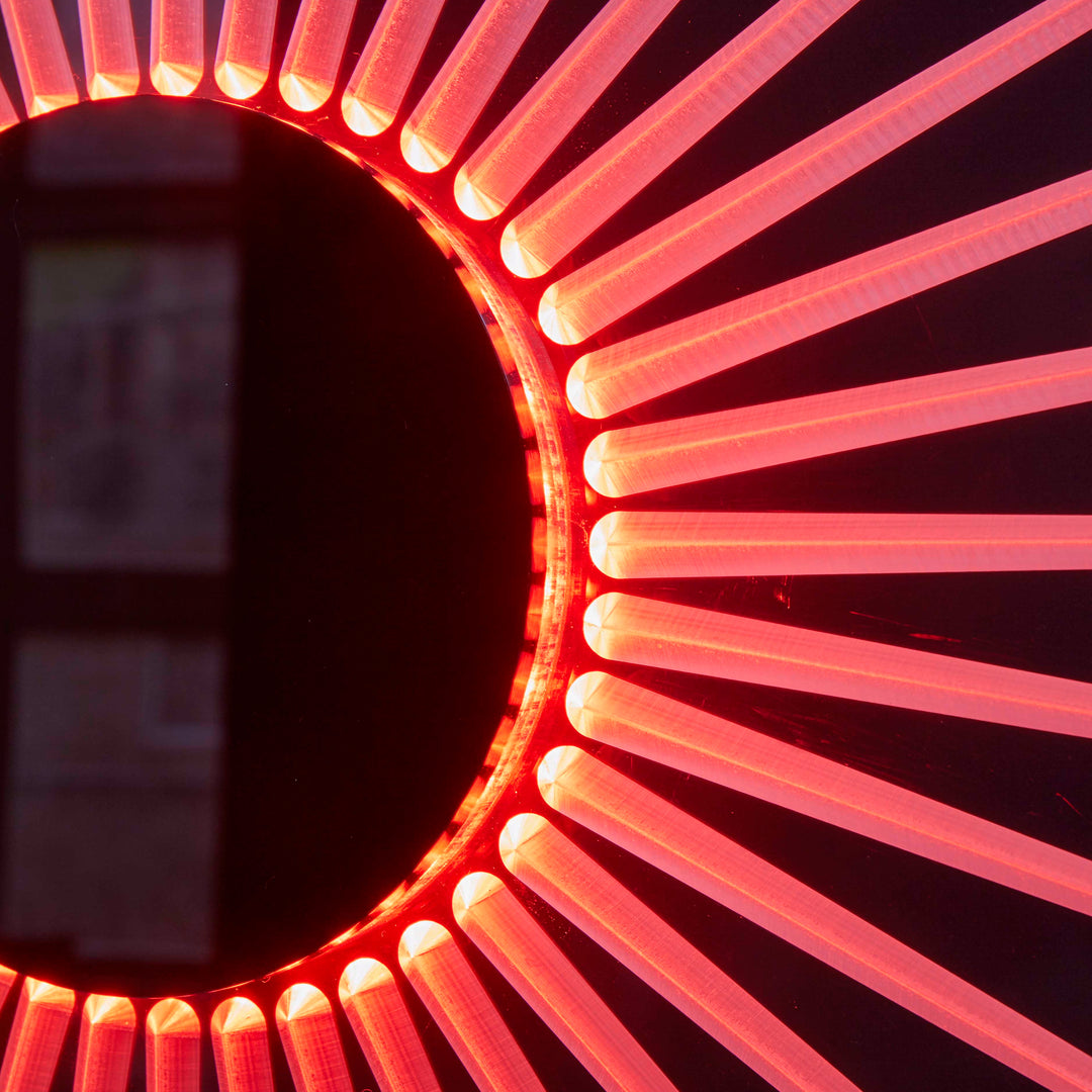 “Iris” by Ben Rousseau – a circular illuminated artwork crafted from engraved acrylic, combining nature’s geometry with digital precision. Red and amber light radiates from the centre, evoking the structure of a human iris in sculptural form.

