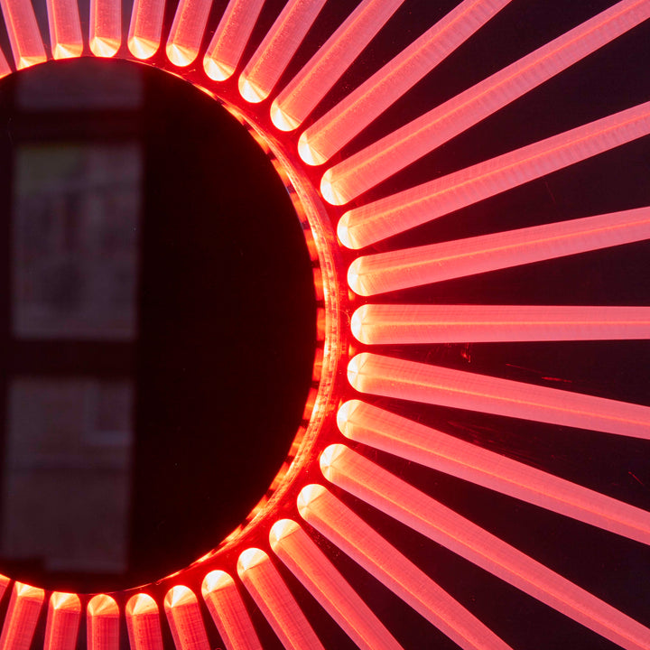“Iris” by Ben Rousseau – a circular illuminated artwork crafted from engraved acrylic, combining nature’s geometry with digital precision. Red and amber light radiates from the centre, evoking the structure of a human iris in sculptural form.

