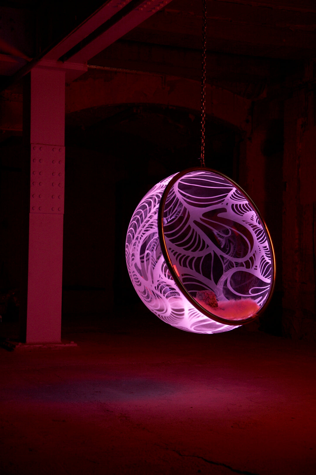 Ben Rousseau, Illuminated Bubble Chair – a limited-edition hanging sphere with engraved acrylic, vibrant pink-purple LED glow, and Mongolian sheepskin cushion featuring INSA’s signature pattern. A cocoon-like statement chair blending art, comfort, and sensory light.