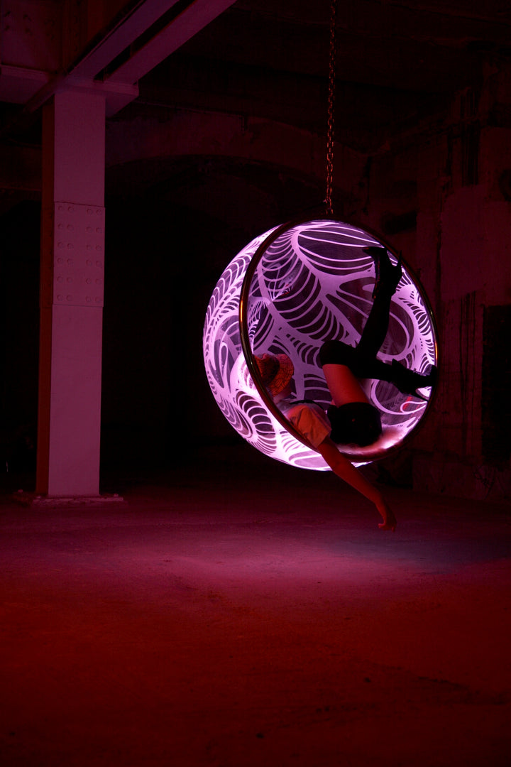 Ben Rousseau, Illuminated Bubble Chair – a limited-edition hanging sphere with engraved acrylic, vibrant pink-purple LED glow, and Mongolian sheepskin cushion featuring INSA’s signature pattern. A cocoon-like statement chair blending art, comfort, and sensory light.