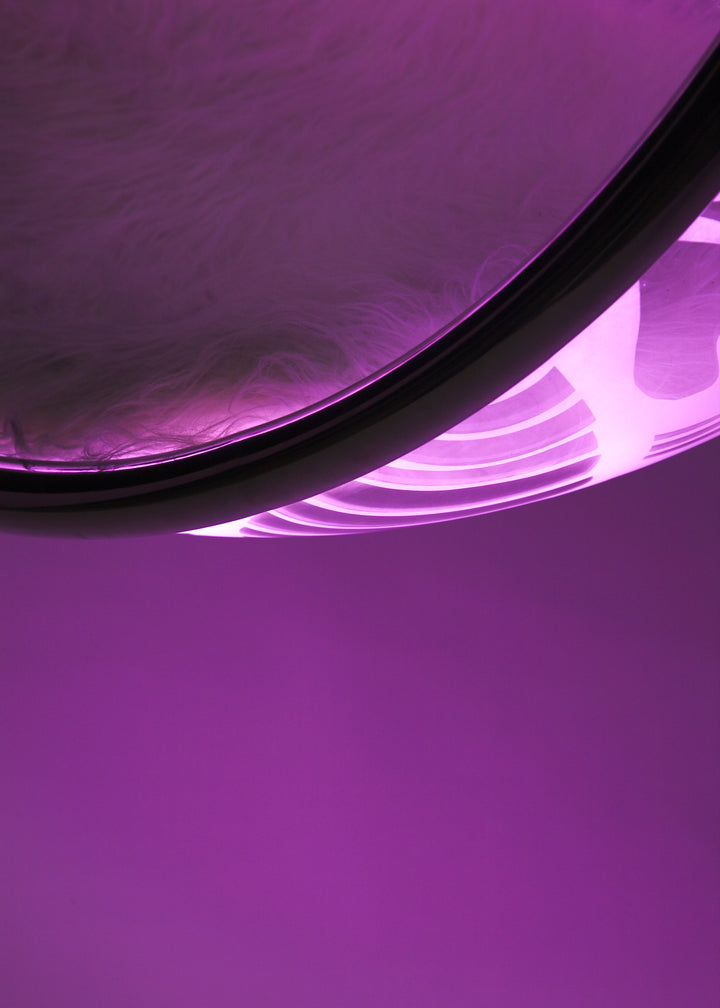 Ben Rousseau, Illuminated Bubble Chair – a limited-edition hanging sphere with engraved acrylic, vibrant pink-purple LED glow, and Mongolian sheepskin cushion featuring INSA’s signature pattern. A cocoon-like statement chair blending art, comfort, and sensory light.