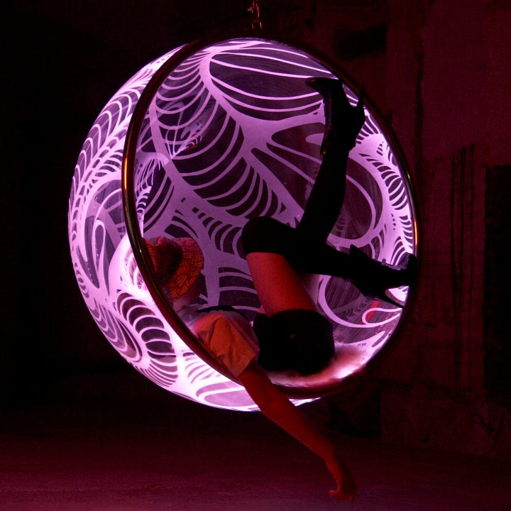 Ben Rousseau, Illuminated Bubble Chair – a limited-edition hanging sphere with engraved acrylic, vibrant pink-purple LED glow, and Mongolian sheepskin cushion featuring INSA’s signature pattern. A cocoon-like statement chair blending art, comfort, and sensory light.