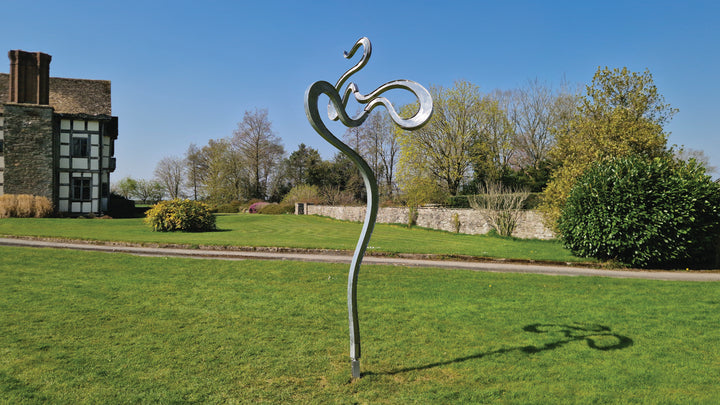 Abstract stainless steel kinetic sculpture featuring fluid, serpentine curves that shift gently with the wind