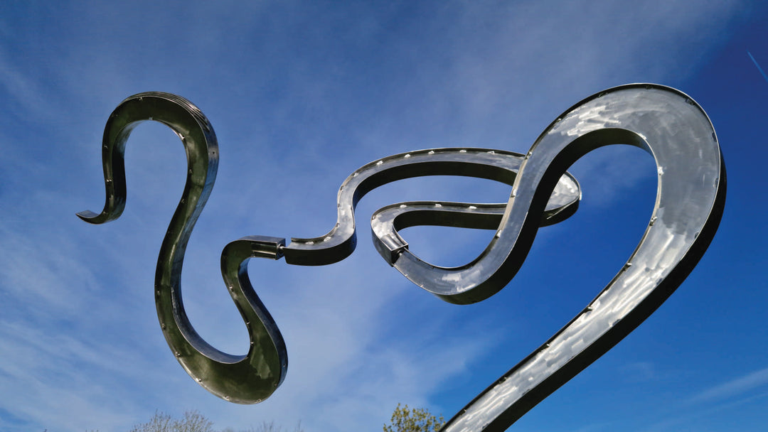 Abstract stainless steel kinetic sculpture featuring fluid, serpentine curves that shift gently with the wind