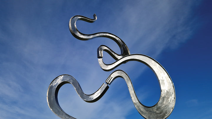 Abstract stainless steel kinetic sculpture featuring fluid, serpentine curves that shift gently with the wind