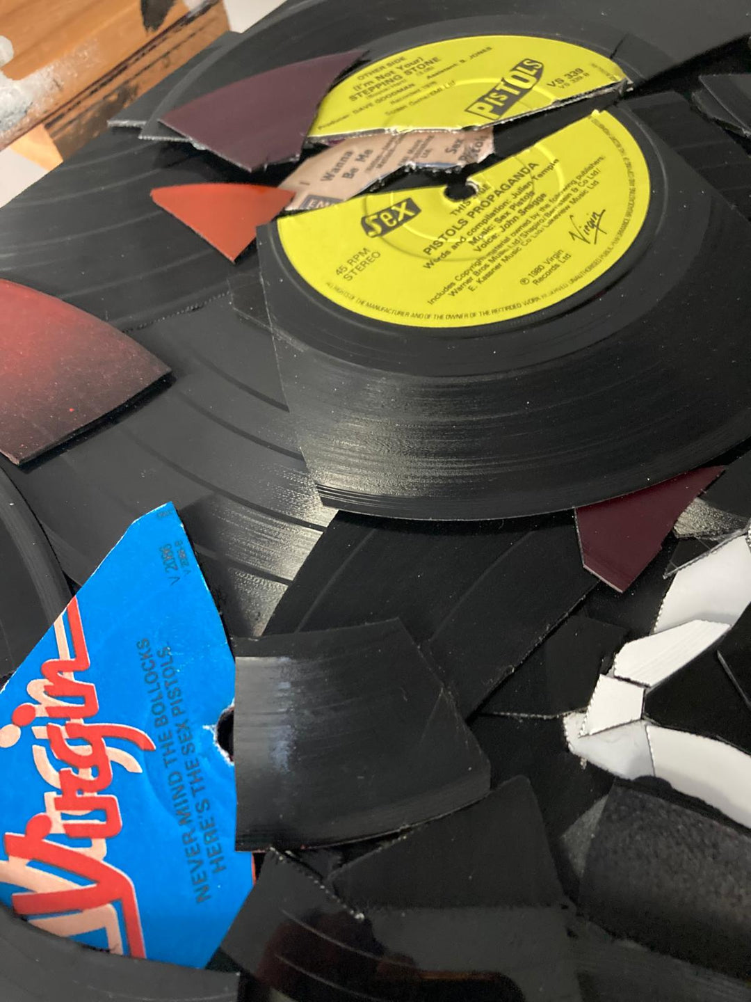 Ed Chapman mosaic artwork featuring the Sex Pistols logo created entirely from destroyed Sex Pistols vinyl records, with fractured black discs and colourful record labels forming a bold punk-inspired composition.