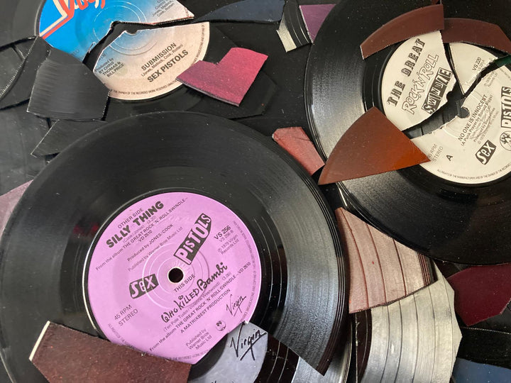 Ed Chapman mosaic artwork featuring the Sex Pistols logo created entirely from destroyed Sex Pistols vinyl records, with fractured black discs and colourful record labels forming a bold punk-inspired composition.